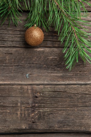 Gold Christmas ball with pine or fir branch on old worn wooden surfaceの写真素材