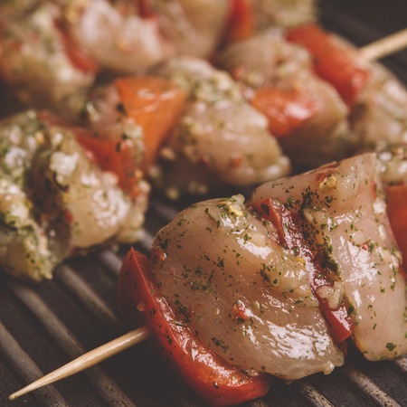 Skewers with raw meat with vegetables on grill panの写真素材