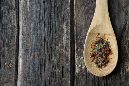 pepper and herbs for seasoning in wooden spoon on old wooden surfaceの写真素材