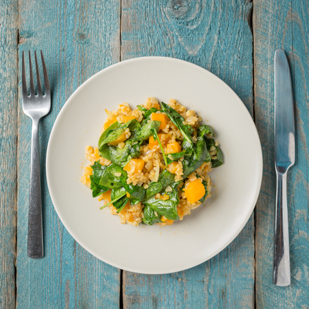 Plate with bulgur and pumpkin with spinach on old blue backgroundの写真素材
