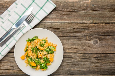Plate with bulgur and pumpkin with spinach on old worn backgroundの写真素材