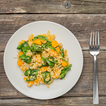 Bulgur with Vegetables:pumpkin, onion and spinach on wooden background - healthy homemade organic vegan vegetarian diet foodの写真素材