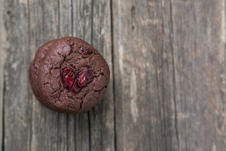 Soft freshly baked chocolate cookies with cranberry on old wooden surfaceの写真素材