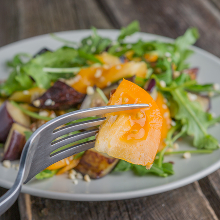 Healthy salad of vegetables - tomatoes, arugula, grilled eggplant and seeds on a plate. Vegan food.の写真素材