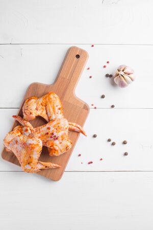 Raw chicken wings on cutting board on white wooden backgroundの写真素材