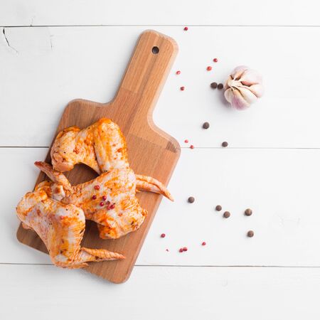 Raw chicken wings on cutting board on white wooden backgroundの写真素材