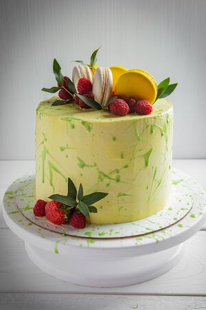 Matcha Green tea cake with macaroon, raspberries decorated with green leaves on white backgroundの写真素材