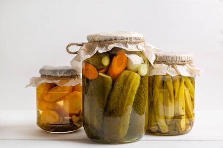 Jars of pickled vegetables: cucumbers, tomatoes, eggplants on rustic wooden background. Marinated and canned food.の写真素材