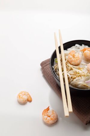 Traditional vietnamese noodle soup pho with shrimps in black bowl on white backgroundの写真素材