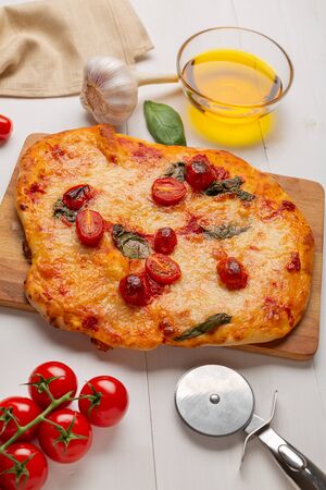 Homemade pizza with tomatoes, garlic ,mozzarella and basil. Top view on white tableの写真素材