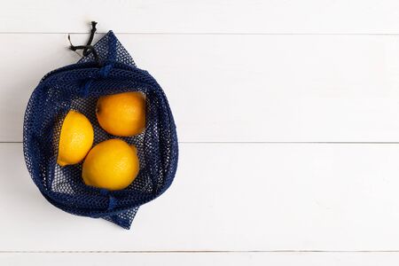 A reusable net bag for grocery shopping filled with fresh lemon on white background. Concept of stop using single-use plastic,zero waste and Eco- friendly living, top view with copy spaceの写真素材