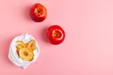 Homemade sun-dried organic crispy apple chips in cloth bag, on pink background with fresh apple. Zero waste, plastic free recycled textile concept. Copy space top viewの写真素材