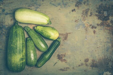 Fresh organic zucchini or green courgette on old metal surface. Top view with copy space. Vintage style. Toned photoの写真素材