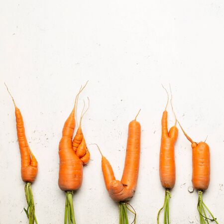 Ugly carrots on a white cracked surface. Ugly food concept, top view.の写真素材