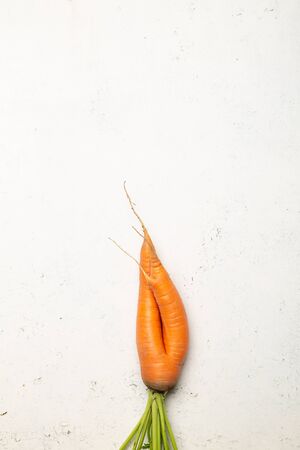 Ugly carrots on a white cracked surface. Ugly food concept, top view.の写真素材