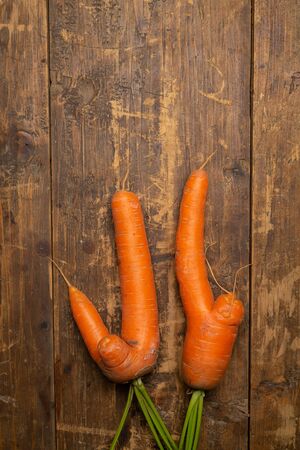 Ugly carrots on wooden background freshly picked from garden. Organic food concept. Top view.の写真素材