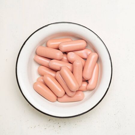 raw sausages in old metal bowl on cracked white background. Top viewの写真素材