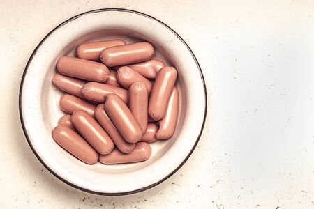 raw sausages in old metal bowl on cracked white background. Top viewの写真素材