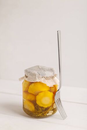 Glass jar with canned squash with fork on white wooden backgroundの写真素材