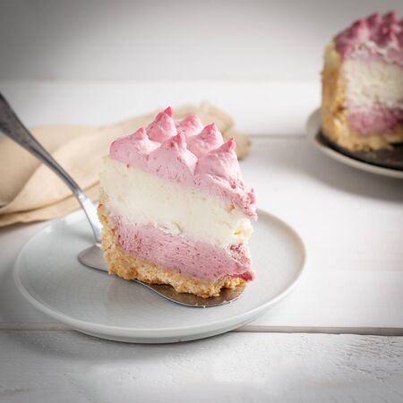 Piece of Delicious homemade cheesecake with berries on white wooden surface.の写真素材