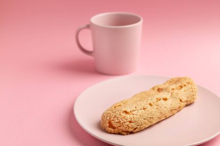 Eclair on the plate. Pink pastel background. Dessert concept, minimalismの写真素材