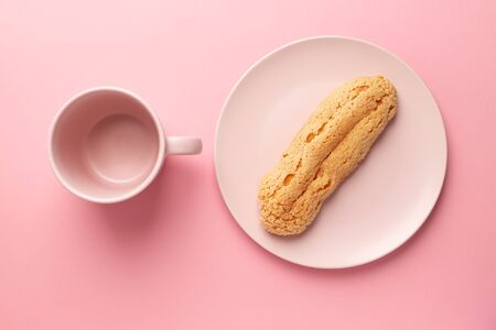 Eclair on the plate. Pink pastel background. Dessert. concept, minimalismの写真素材