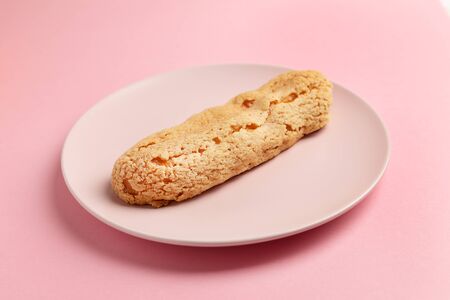 Eclair on the plate. Pink pastel background. Dessert concept, minimalismの写真素材