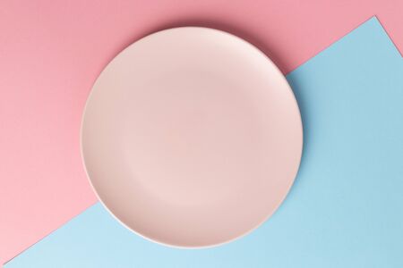 Empty pink plate on blue and pink pastel background. Top viewの写真素材