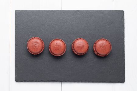 Homemade chocolate macaroons with chocolate filling on black slate plate. Top viewの写真素材