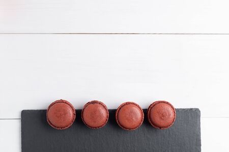 Homemade chocolate macaroons with chocolate filling on black slate plate. Top viewの写真素材