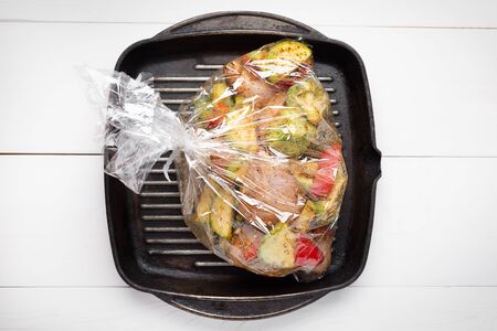 Uncooked vegetables with pieces of meat on pan in the oven baking bag. Top view .の写真素材