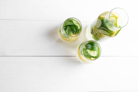 Sassy diet water. Cucumber, lemon, mint lemonade in glasses on white wooden table. Top view with copy spaceの写真素材
