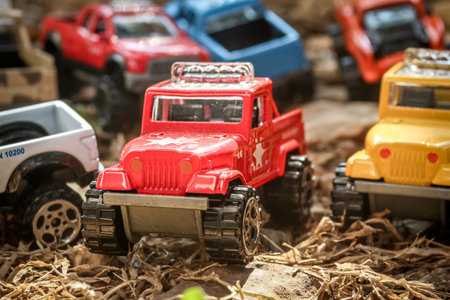 Seven miniature 4x4 trucks in assorted colors parked on dry rural grass, simulating an adventurous convoy. Front view with several vehicles softly blurred in the background.の写真素材