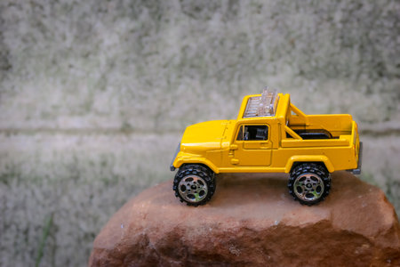 Miniature 4x4 pickup truck model in bright yellow on simulated rocky mountains. Captured from a high angle with soft background. Fun and creative off-road adventure concept.の写真素材