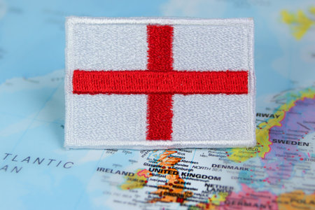 Hand embroidered St Georgeâs Cross flag positioned on the map of England, Europe. Eco friendly theme promoting sustainable travel and UK landmarks.の写真素材