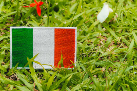 Italy national flag in embroidered fabric, placed on natural grass with copy space on right. Environmental, handmade concept from Europe.の写真素材