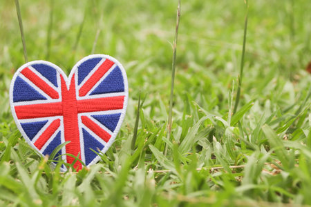 Heart with United Kingdom flag on green grass background, Union Jack heart crafted from thread on grass, eco friendly symbol of love and nature, space for text on right.の写真素材