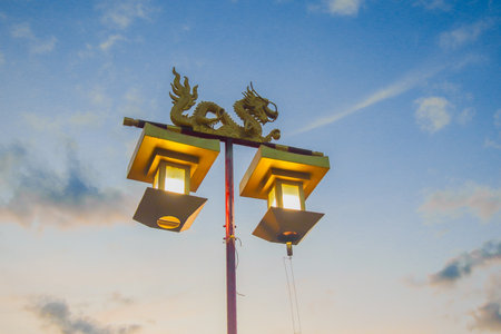 Low angle golden dragon lantern on red pole glowing warmly at dusk, blue and gold sky creating cultural and festive mood.の写真素材