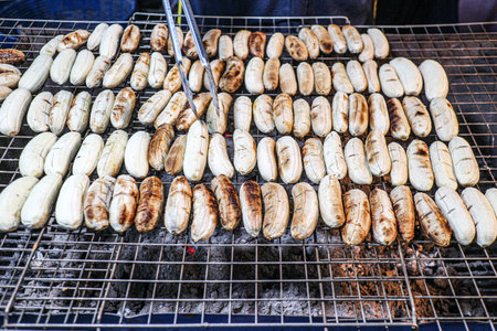 Close up grilled Thai bananas on charcoal stove, traditional street food dessert with sweet aroma, classic Thai local snack.の写真素材