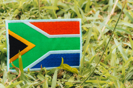 Flag of South Africa on green grass. Eco friendly embroidered South Africa flag (ZA) on grass under warm natural light in Africa. Symbol of climate change awareness and Earth Day.の写真素材
