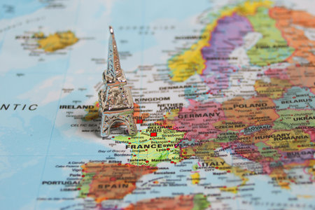 Small metallic Eiffel Tower on map marking France, symbolizing Paris travel, European holidays, and vacation planning ideas.の写真素材