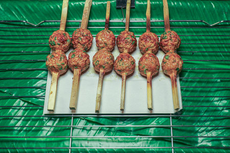 Thai style grilled meatballs on skewers with banana leaf on grill. Made from spicy fish paste, coconut and herbs. Authentic Thai street food concept.の写真素材