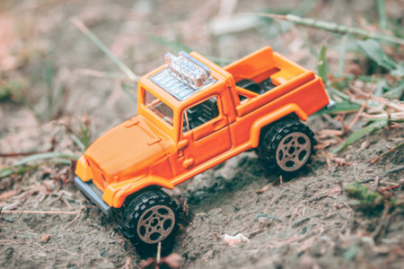 Toy car in the mud. Mini 4x4 pickup truck model off-road in forest diorama, front wheel trapped. Symbolizes adventure, challenge and rugged outdoor lifestyle.の写真素材