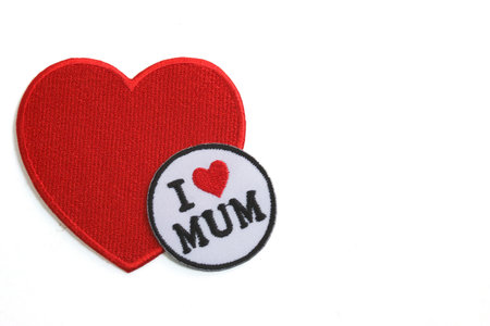Red heart embroidery with I LOVE MUM text inside circle on white background with space for text. Handmade craft art celebrating Motherâs Day and family love.の写真素材