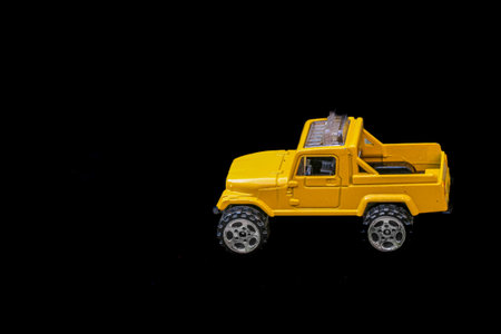 Miniature yellow pickup truck model on black background, side profile aligned to the right with open space for text or branding on the left. Clean, commercial layout.の写真素材