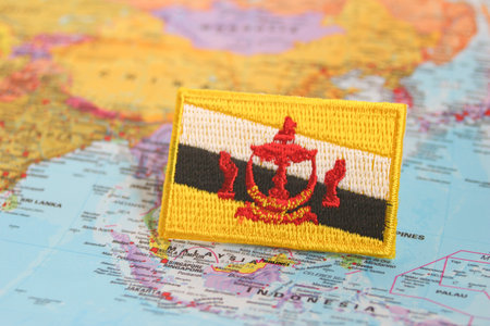 Brunei national flag in an eco-friendly fabric design, resting on a world map at Bruneiâs geographic location. Ideal for travel, culture, and green lifestyle themes.の写真素材