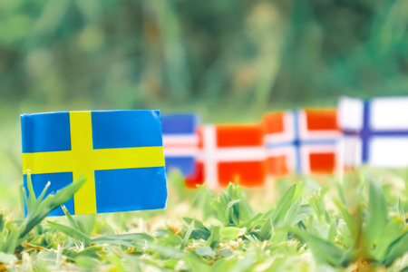 Sweden flag standing on green field, Nordic flags softly visible in the distance. Eco-friendly, perfect for nature, sustainability and Scandinavian content.の写真素材