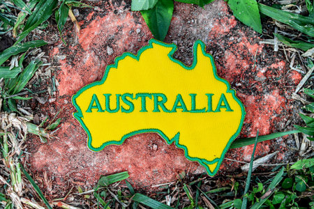 Stitched fabric map of Australia with central text, set on old rock with leafy border. Eco-friendly and climate-awareness image with natural tone.の写真素材