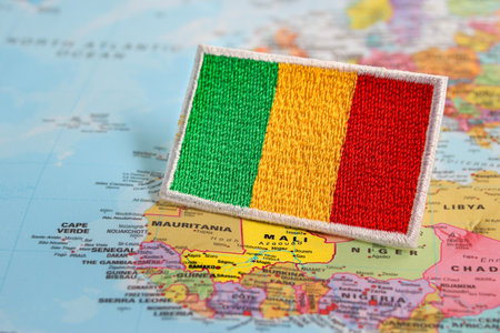 Embroidered Mali flag on a world map showing its West African location. Fabric and thread design promotes eco-tourism, travel, and cultural awareness.の写真素材
