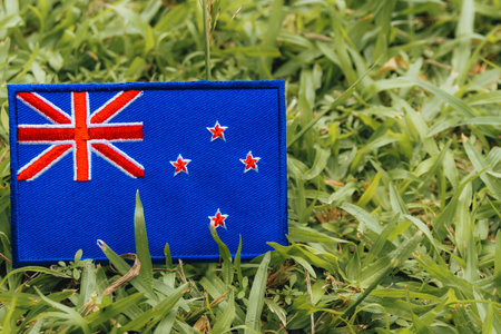 Fabric-stitched New Zealand flag on lush green grass, symbolizing eco-friendly values, patriotism, and environmental awareness. Space for text included.の写真素材